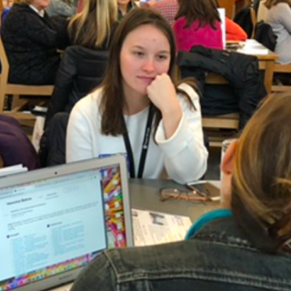 Teachers discussing a Reader Report shown on a computer