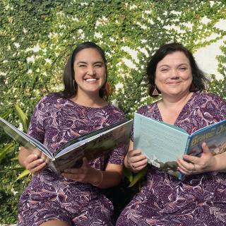Two women holding books smiling